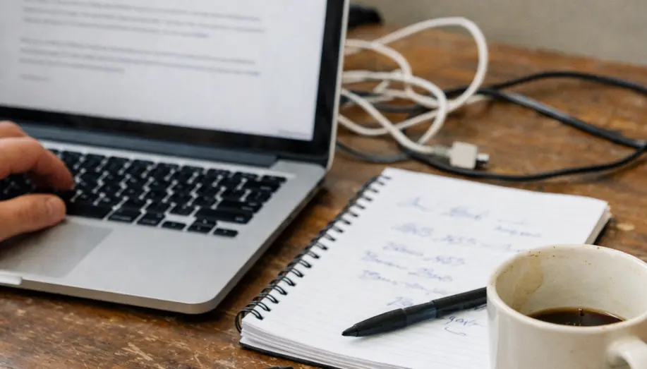 Content creation workspace, clean aesthetic, featuring a laptop open to a text editor drafting